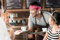 Waiter serving coffee in Asian cafe to women and man