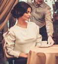 Waiter serving cup of coffee to beautiful woman Royalty Free Stock Photo