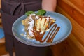 Waiter serving ice cream dessert in restaurant or diner. Eating out concept. Apple pie with ice cream and caramel sauce