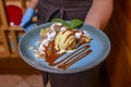 Waiter serving ice cream dessert in restaurant or diner. Eating out concept. Apple pie with ice cream and caramel sauce