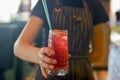 Waiter serving red alcohol cocktail. Seasonal summer drink. Young waitress at work in restaurant or cafe. Royalty Free Stock Photo