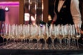 Waiter serving row of glasses of white champagne on tray in restaurant closeup. Pouring sparkling wine into glasses Royalty Free Stock Photo