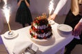 Waiter in the shape of the restaurant pulls out a beautiful wedding yogurt cake with the inscription love and burning fires with s Royalty Free Stock Photo