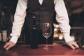 Waiter stands before tray with bottle of wine and empty glass in restaurant. Wine tasting concept. Royalty Free Stock Photo