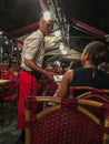 Waiter talks with diner at a Paris cafe at night