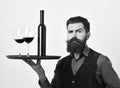 Waiter with tray, bottle and glass of red wine. Barman with confident face holds italian drink Royalty Free Stock Photo