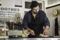 A waiter wearing an apron is preparing a delicious sandwich made of beef and hummus sauce. Small entrepreneur working alone in his Royalty Free Stock Photo