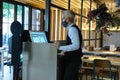 Waiter wearing face mask checking the tables on a counter touch screen. New normal in restaurants