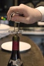 The waiters hand opens a bottle of vintage wine with a corkscrew. Close up Royalty Free Stock Photo