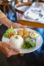 waiters in Indonesia carry white plates containing the food that will be served. the food consists of vegetables, meat and