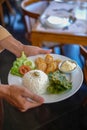 waiters in Indonesia carry white plates containing the food that will be served. the food consists of vegetables, meat and