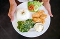 waiters in Indonesia carry white plates containing the food that will be served. the food consists of vegetables, meat and