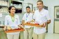 Waiters and waitress team smiling with trays in the kitchen