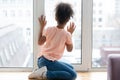 Waiting african american young girl sitting alone on windowsill.,