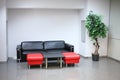 Waiting area with black sofa and two red chairs in