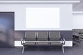 Waiting area with blank white mock up banner on wall in modern interior with concrete flooring, seats and plants. Royalty Free Stock Photo