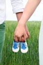 Waiting for a baby boy. A woman and a man hold baby`s shoes in nature