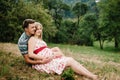 Wait baby. happy family. pregnant woman with beloved husband sitting on grass, admiring landscape. round belly. The sincere tender