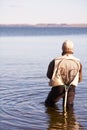 Waiting for the big one. A lone fisherman stands knee-deep in the water. Royalty Free Stock Photo