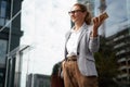 Happy successful business woman wearing eyeglasses and classic wear holding mobile phone and smiling while standing Royalty Free Stock Photo