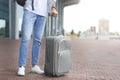 Millennial man standing with luggage at airport exterior