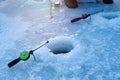 Waiting for fish bite, ice fishing rod ready in a hole on a narrow frozen river