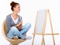 Waiting for inspiration to strike. Studio shot of a young female artist sitting on a chair looking at a blank canvas. Royalty Free Stock Photo