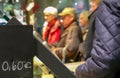 Waiting line at a bakery behind a price board with deliberately blurred people