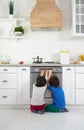 Waiting for pie. Curious little latin boys, twins watching pie baking in the oven, crouching down in the kitchen at home Royalty Free Stock Photo