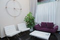 Purple sofa and white armchair. Iron and wooden clocks . Interior design . Bottom and white curtain . Entrance to the beauty salon Royalty Free Stock Photo