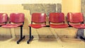 Waiting room, red chairs placed against a deteriorated wall