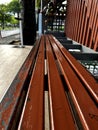 The waiting seats for the bus have long red seats.