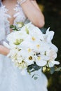 Bride holds a bouquet of roses and orchids Royalty Free Stock Photo