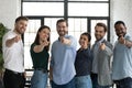 Friendly multiethnic teammates pointing fingers at camera choosing new colleague