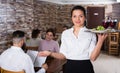 Waitress bringing order for guests in traditional cafe Royalty Free Stock Photo