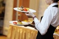 Waitress carrying three plates with meat dish