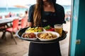 Waitress carrying a tray with tasty looking food in outdoor restauran. Generative AI