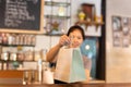 Waitress at counter giving eco friendly paper bag with take away drink in cafe. Royalty Free Stock Photo