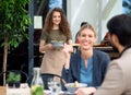 Waitress with face mask serving happy couple outdoors on terrace restaurant.