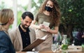 Waitress with face mask serving happy couple outdoors on terrace restaurant.