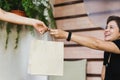 Waitress giving eco friendly paper bag to cheeful customer take out in cafe outdoor.