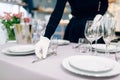 Waitress in gloves puts the knife, table setting