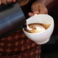 Waitress hands pouring milk making cappuccino