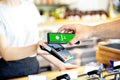 Waitress holding card reader for man paying by smartphone at store, Customer using mobile phone for payment Royalty Free Stock Photo