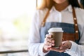 A waitress holding and serving a paper cup of hot coffee Royalty Free Stock Photo