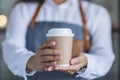 A waitress holding and serving a paper cup of hot coffee Royalty Free Stock Photo