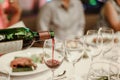 Waitress is pouring red wine in glasses for wine tasting event on the table in restaurant . Royalty Free Stock Photo