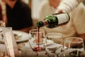 Waitress is pouring red wine in glasses for wine tasting event on the table in restaurant . Royalty Free Stock Photo