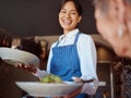 Waitress in a restaurant, serving customer her food, healthy salad and gives service with a smile. Woman in the