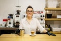 Waitress in a restaurant smiling behind the bar. On the bar a coffee with milk